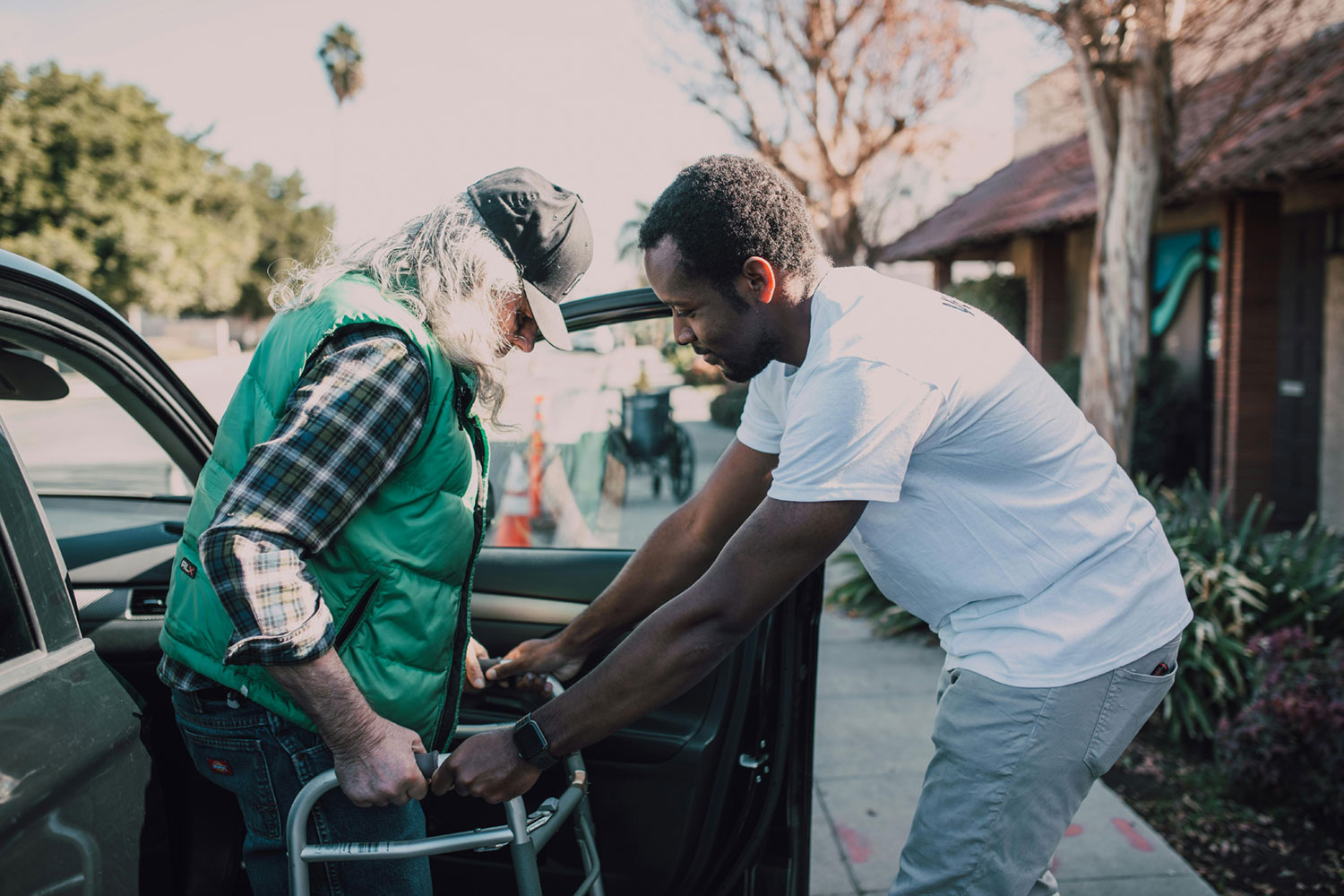 Man helping older man out of car with walker